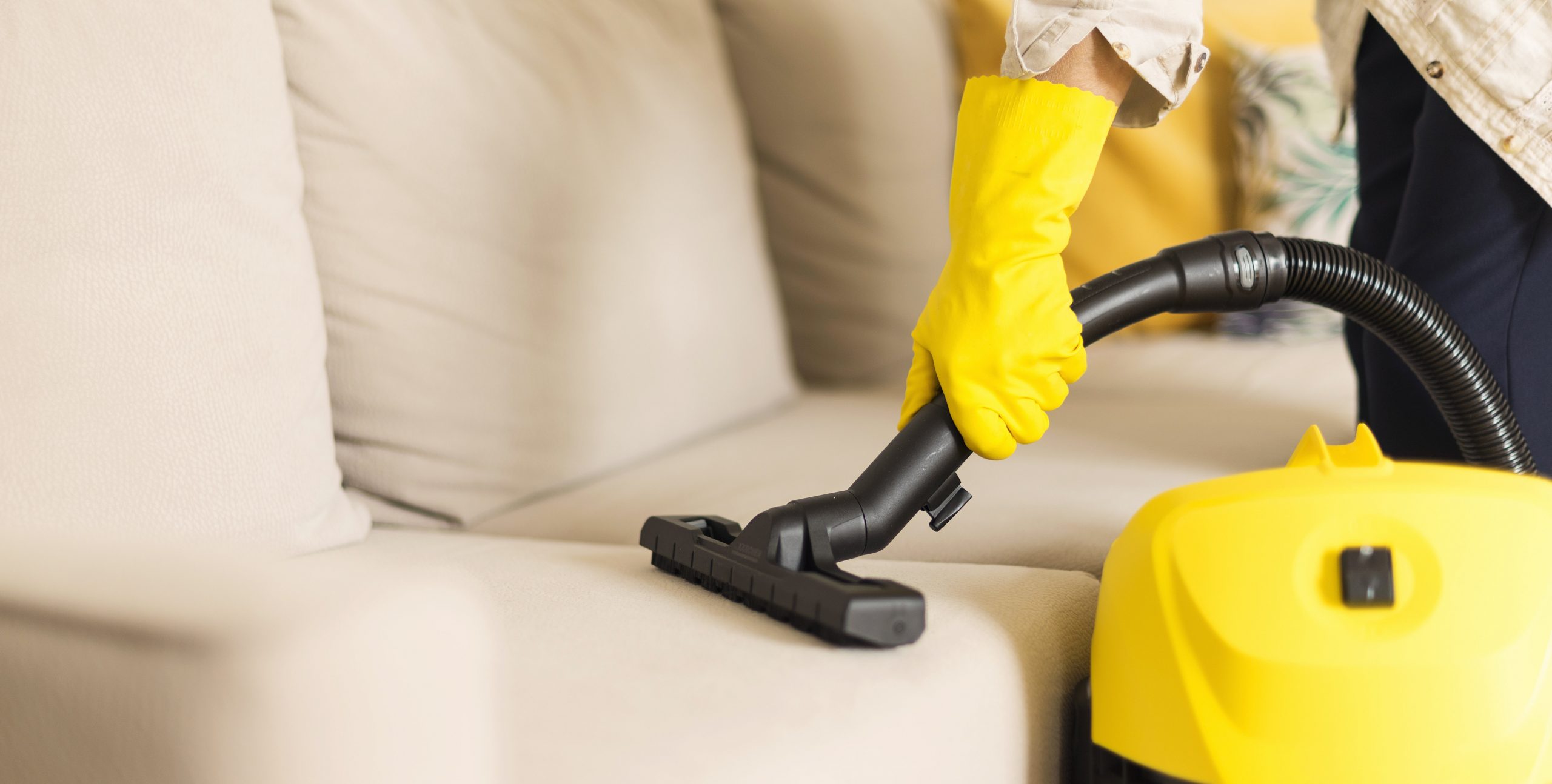 woman-cleaning-sofa-with-yellow-vacuum-cleaner-cop-WKL4JYE-scaled.jpg